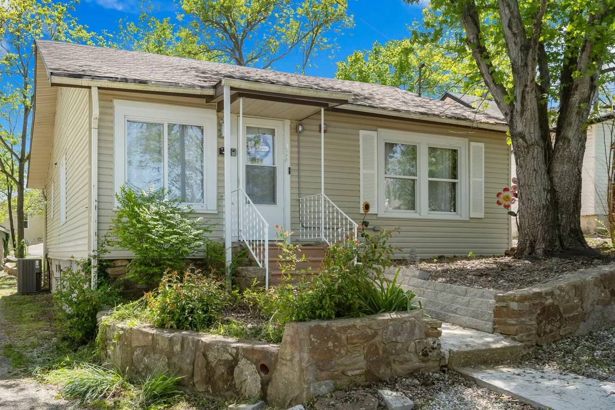 The exterior of a welcoming home is shown with a front porch, landscaped garden, and a stone pathway. The inviting outdoor space is perfect for enjoying the fresh air, sipping coffee, or hosting a family barbecue in the evening.