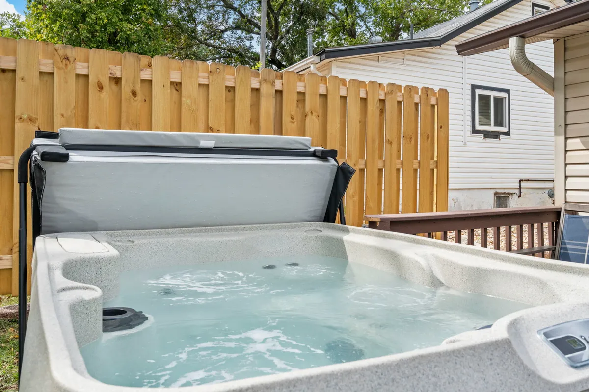 This image features a private hot tub nestled in a tranquil backyard setting, bordered by a wooden fence and surrounded by lush greenery. The scene is peaceful and suggests a relaxing escape within the city, ideal for unwinding after a day of urban adventures.
