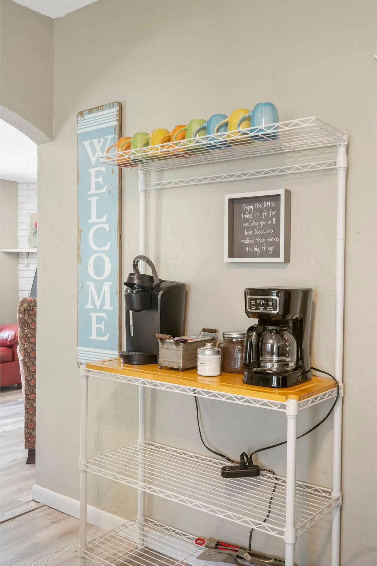 This image features a cozy coffee station with a welcome sign, colorful mugs, and a coffee maker. The scene is inviting, suggesting a spot for guests to enjoy a relaxed morning or connect with others over coffee. The atmosphere is warm and sociable, highlighting the ease and comfort of dropping in for a short stay.