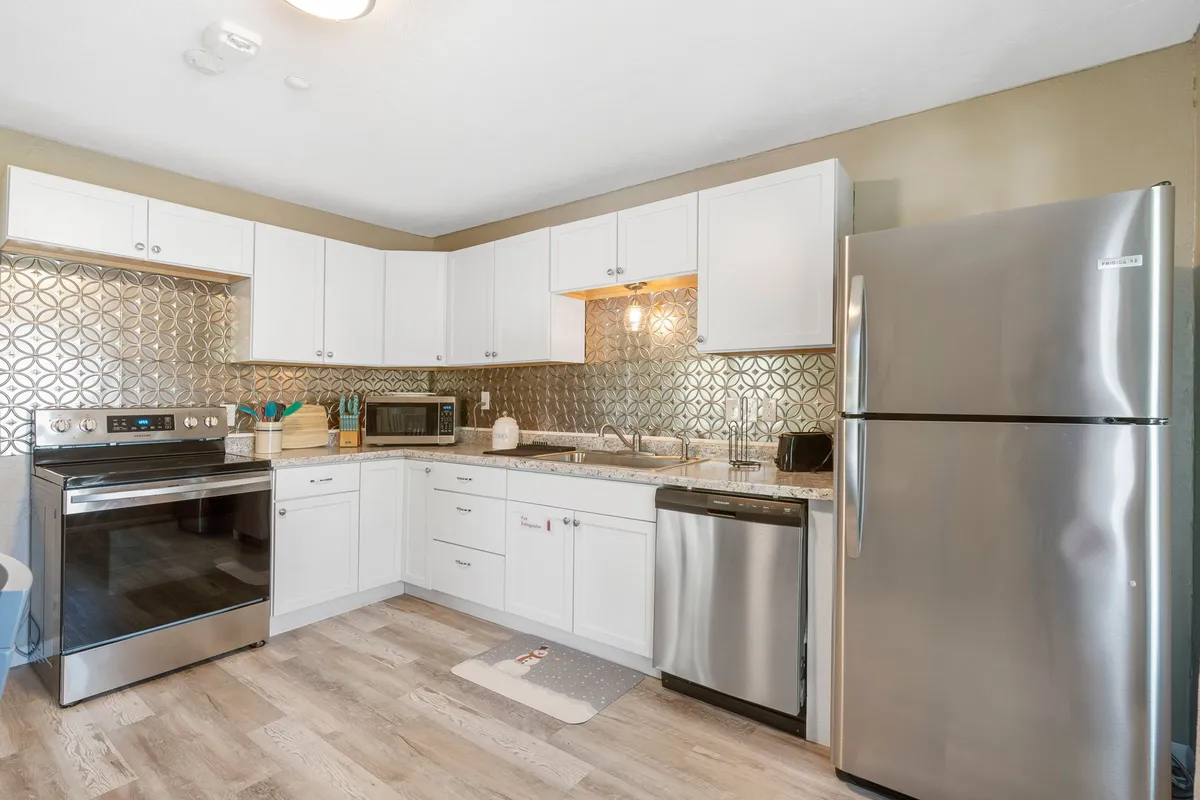 A modern kitchen with stainless steel appliances, a decorative backsplash, and a spacious island, perfect for group meals and pre-night-out gatherings.